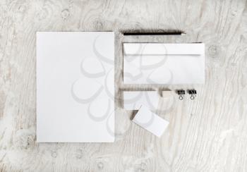 Photo of blank stationery set on light wooden table background. Corporate identity template. Branding mockup. Sheets of paper, letterhead, business cards, envelope and pencil.