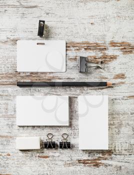Photo of blank stationery set. Bank business cards, pencil, eraser, badge and sharpener on vintage wood table background. Template for design portfolios.Top view.