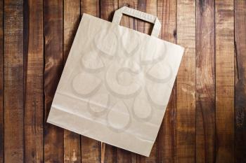 Recycled craft paper shopping bag on vintage wooden table background. Top view.