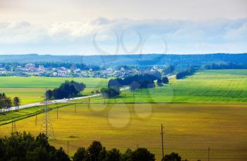 Bright summer countryside landscape. Meadows, fields, trees, road and houses in the countryside. Minsk region, Belarus