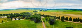 Panoramic rural area. Green fields, meadows, trees, pond, roads and sky with clouds. Minsk region Belarus
