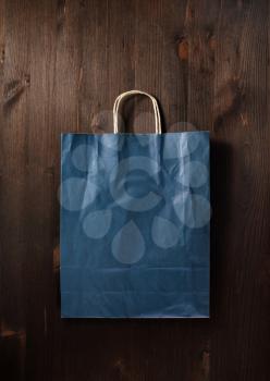Blank blue paper shopping bag on wooden background. Flat lay.