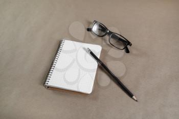 Blank paper notebook with glasses and pencil on craft paper background. Business concept. Stationery set. Responsive design template.
