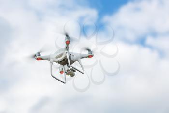 Flying quadrocopter drone against the sky with clouds. Quad copter drone. Unmanned camera.