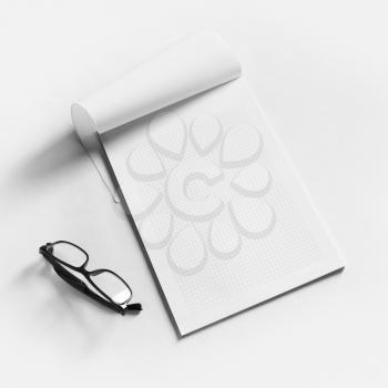 Blank copybook and glasses on white paper background. Responsive design mockup.