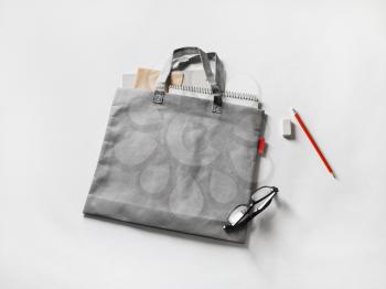Blank gray shopping canvas bag, glasses, pencil and eraser on paper background.