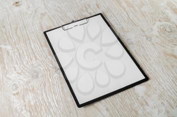 Paper clipboard with blank letterhead on light wooden background with plenty of copy space.