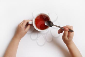 Baby hands with cup of aromatic tea on white background.