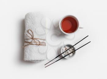 Beauty spa concept. Towel, tea cup and incense for spa treatments on white paper background. Flat lay.