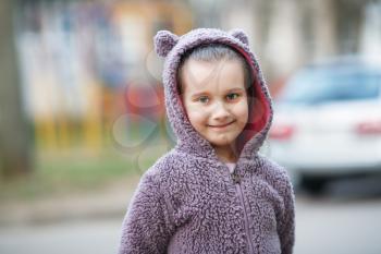 Smiling child girl in fluffy sweatshirt with hood outdoors.