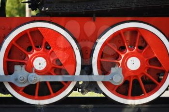 Two old red steam locomotive wheels on rails closeup.