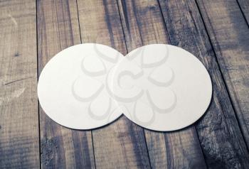 Two blank white beer coasters on vintage wooden table background. Responsive design mockup.