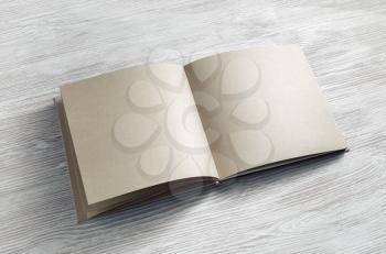 Blank notebook or book of kraft paper on light wooden background. Responsive design mockup.