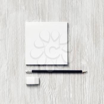White square notepad, pencil and eraser on light wooden background. Blank stationery template. Flat lay.