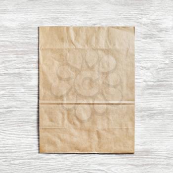 Kraft paper package on light wood table background. Responsive design template. Flat lay.