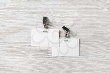 Photo of two blank white plastic badges mockup on light wooden background. Id cards mock up. Space for text. Flat lay.
