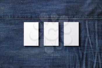 Three blank business cards on denim background. Branding mockup. Flat lay.