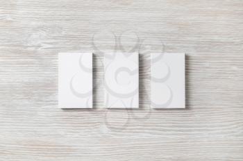 Three blank business cards on light wooden background. Branding mockup. Flat lay.