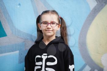 Portrait of child girl in black sweatshirt against wall background. Selective focus.