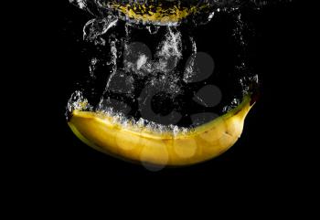 Banana falling in water with splash on black background.