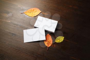 Photo of blank business cards and autumn leaves on wood table background. Template for branding ID.