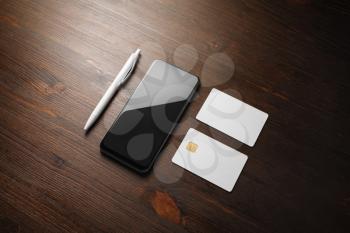 Smartphone, credit cards and pen on wooden background. Blank branding mockup.