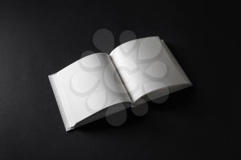 Photo of opened blank square book on black paper background.