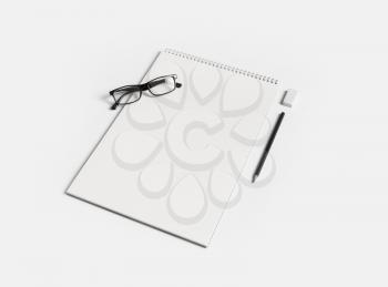 Blank notebook, glasses, pen and eraser on white paper background. Notepad and stationery for placing your design.