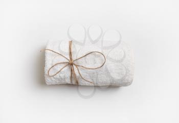 Blank towel tied with a rope on white paper background. For spa treatments or in a hotel. Flat lay.