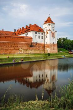 Mir, Belarus - August 04, 2017: Ancient medieval castle with towers in Mir, Belarus. Fortress and its reflection in the lake. UNESCO World Heritage. Vertical shot.