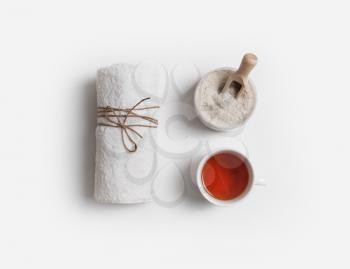 Towel, sea salt and tea cup on white paper background. Spa and beauty concept. Flat lay.