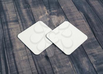 Two blank white beer coasters on vintage wooden background. Responsive design mockup.
