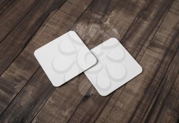 Two blank white beer coasters on vintage wooden background. Responsive design mockup.