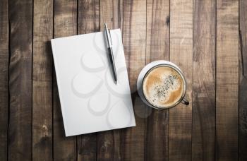 Blank book, pencil and coffee cup on wooden table background. Stationery elements. Template for placing your design.