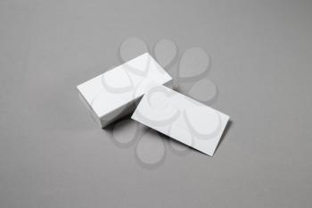 Blank white business cards on grey paper background. Mockup for branding identity. Template for graphic designers portfolios. Top view.
