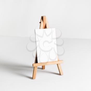 Photo of blank business cards on mini easel at white paper background.