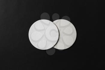 Two blank white beer coasters on black paper background. Responsive design mockup. Flat lay.