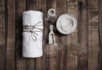 Towel and sea salt on wood table background. Beauty and spa concept. Flat lay.