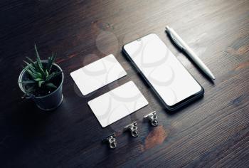 Corporate identity template on wood table background. Smartphone, business cards, pen and plant.