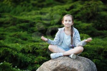 Child girl meditating in the park. Healthy lifestyle. Meditation and yoga concept. Selective focus.