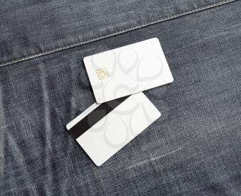 Photo of blank white plastic credit cards on denim background. Two bank cards. Front and back view. Flat lay.