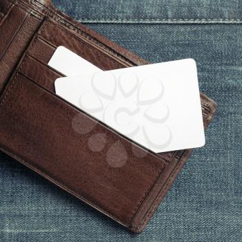 Blank business card or discount card in leather wallet on denim background. Copy space for text. Flat lay.