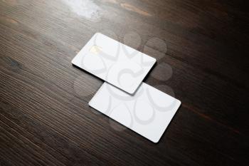 Photo of two blank credit cards on wood table background. White bank cards.