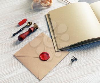 Blank retro stationery on light wooden background. Envelope with wax seal, stamp, book and spoon.