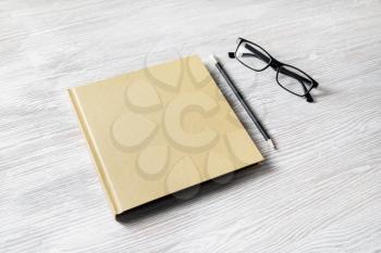 Photo of blank closed book, glasses and pencil on light wood table background. Responsive design template.