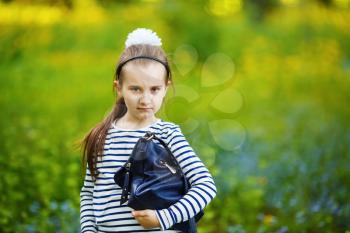 Girl with handbag posing outdoors. Child in the park. Selective focus.