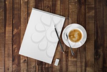 Blank sketchbook, pencil, eraser and coffee cup on wood table background. Stationery elements. Template for placing your design. Flat lay.