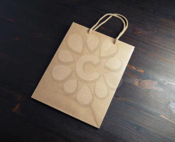 Blank kraft paper bag on wooden background. Responsive design mockup.