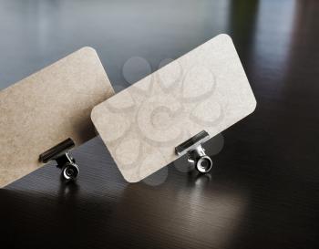 Photo of blank kraft business card on black wooden background. Mock-up for branding identity.