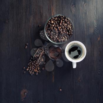 Still life with coffee cup, roasted coffee beans and ground powder on vintage wooden kitchen table background. Top view. Flat lay.
